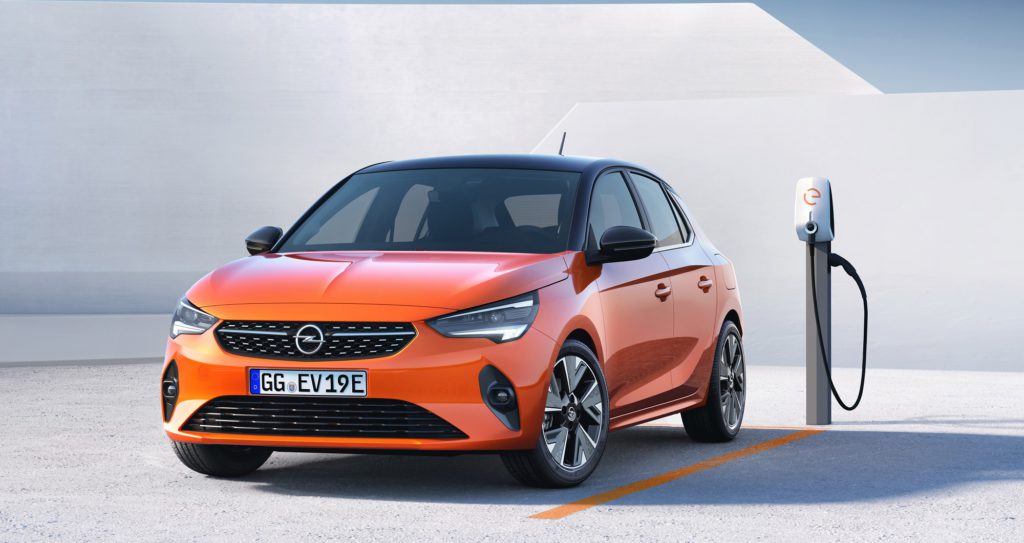 Orangefarbener Opel E-Corsa auf Parkplatz mit Elektro Tanksäule